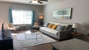 Una sala de estar moderna con sofá, sillones, una mesa de centro y un cuadro en la pared.