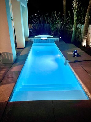 Uma piscina retangular com borda azulejada e ofurô integrado.