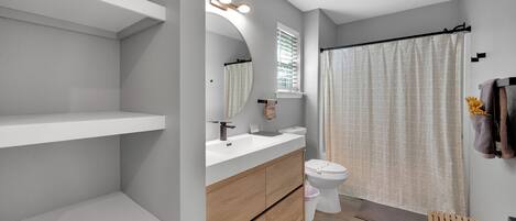 A modern bathroom with a white vanity, a toilet, and a shower curtain.