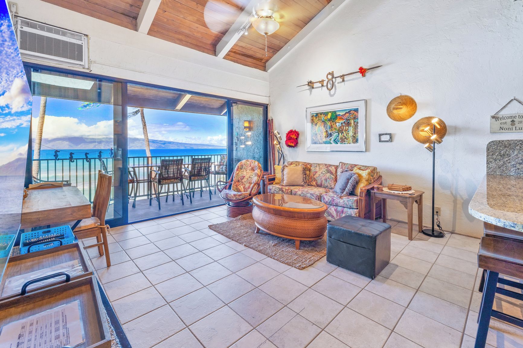 Un vaste espace de vie avec un balcon donnant sur la mer, aménagé avec un canapé, des fauteuils et une table basse.