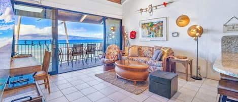 Un vaste espace de vie avec un balcon donnant sur la mer, aménagé avec un canapé, des fauteuils et une table basse.