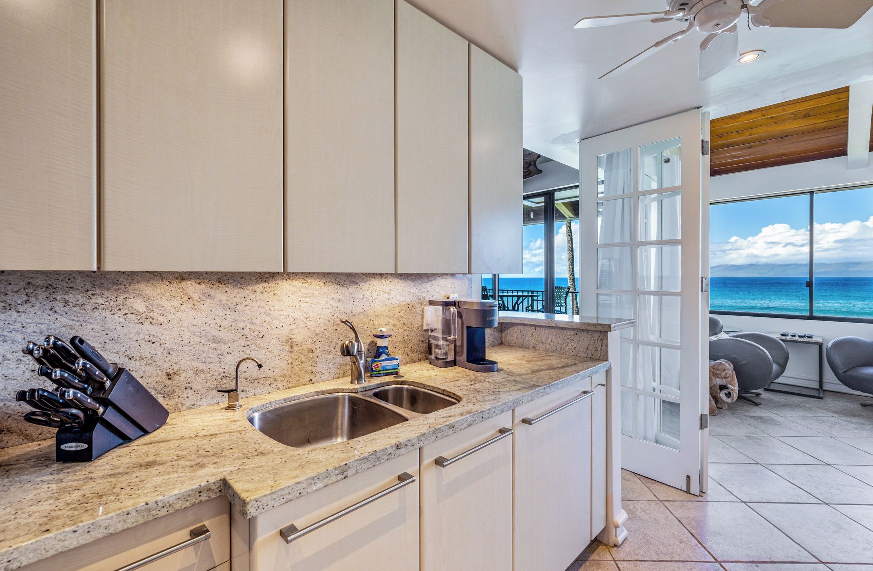 Una cocina moderna con encimeras de granito, electrodomésticos de acero inoxidable y vistas al océano.