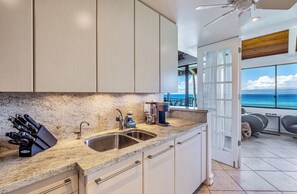 A modern kitchen with granite countertops, stainless steel appliances, and a view of the ocean.