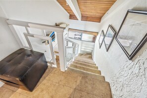 Un escalier avec une rampe, un banc en cuir marron et un mur orné de tableaux encadrés.