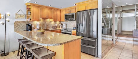 A modern kitchen with granite countertops, stainless steel appliances, and wooden cabinets.