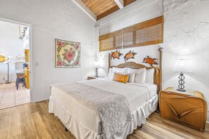 A bedroom with a bed, bedside tables, a lamp, a decorative wall piece, and a wooden ceiling.