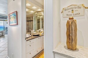 A hotel bathroom with a large mirror, two sinks, and a wooden sculpture on the counter.