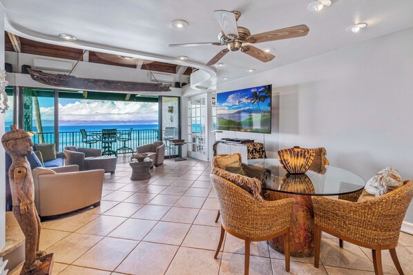 A spacious living area with a large glass door leading to a balcony with a view of the ocean.