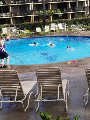 Ein Swimmingpool mit Liegestühlen und einer Person am Beckenrand.