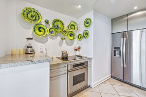 A modern kitchen with a stainless steel refrigerator, a built-in oven, and a granite countertop.