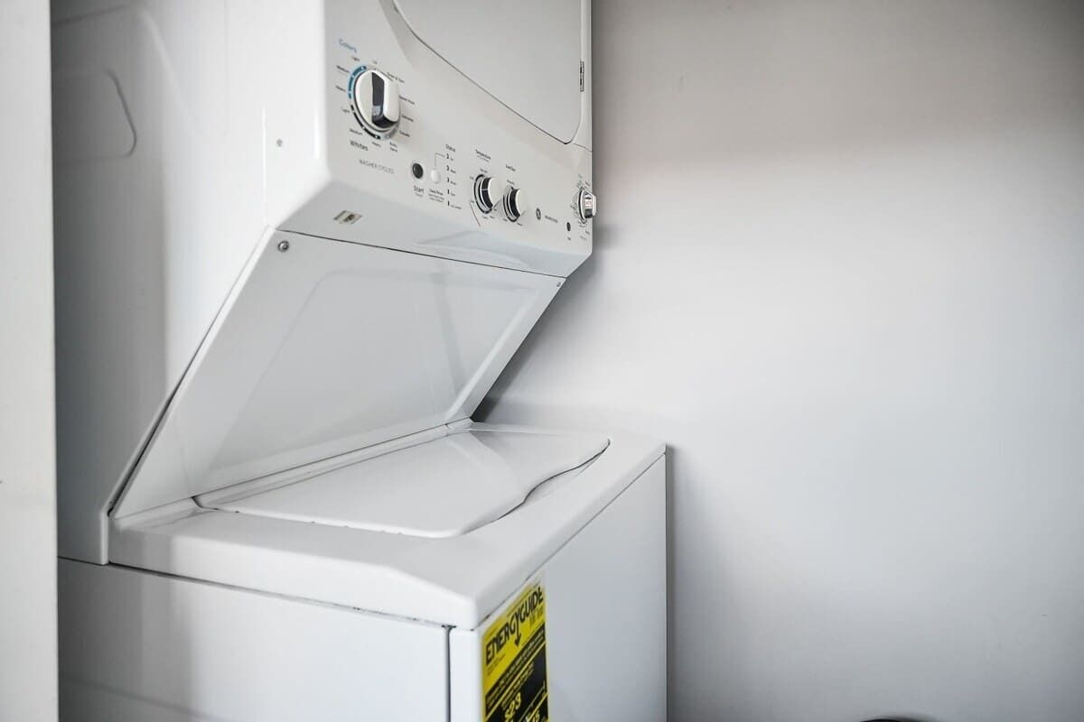 A white washing machine with a control panel and a yellow caution sign.