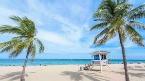 Une plage bordée de palmiers et sur laquelle se trouve une tour de surveillance des sauveteurs.