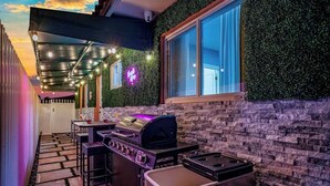 Une terrasse extérieure avec un barbecue, un chemin en pierre et une fenêtre donnant sur le ciel.