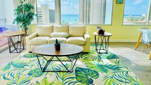 A living room with a sofa, coffee table, and a view of the ocean.