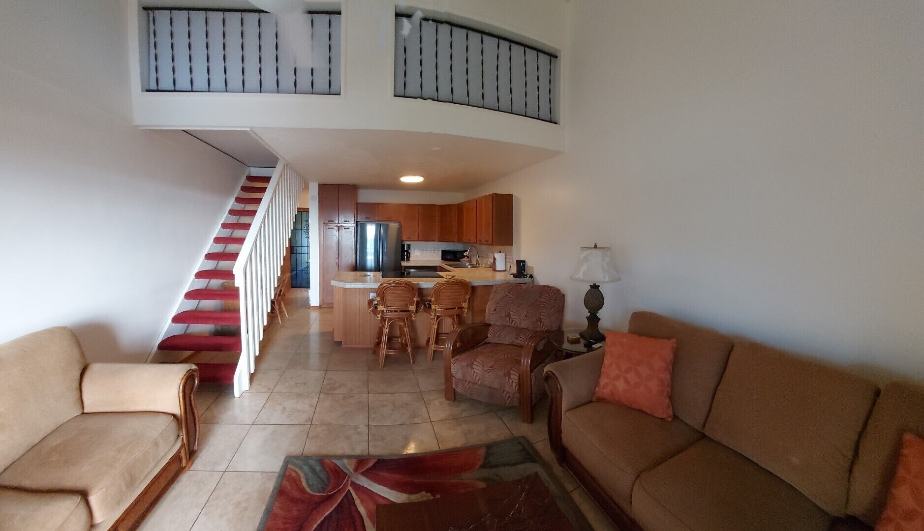 A spacious living area with a staircase, a kitchen, and a dining area.