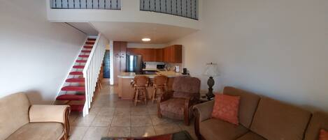 A spacious living area with a staircase, a kitchen, and a dining area.