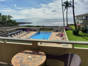 Área da piscina com espreguiçadeiras e vista para o oceano.