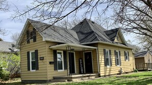 A two-story house with a front porch, a mailbox, and a 'WELCOME' sign.