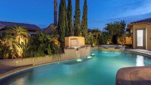 Una piscina con jacuzzi, rodeada de árboles altos y un techo de tejas.