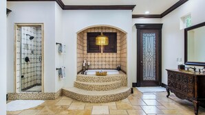 Un baño con una bañera independiente, cabina de ducha de cristal y un espejo decorativo.