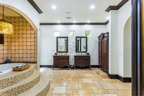 Un baño con dos lavamanos, una bañera y un espejo decorativo.