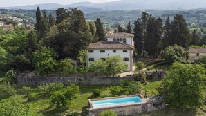 A villa with a swimming pool, surrounded by greenery and a stone wall. - Villa Poggio Cherici by MMega (Rignano sull'Arno)