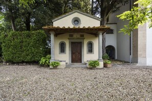 A small building with a tiled roof, a wooden door, and a circular window above the door.