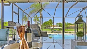 Un espacio al aire libre con paredes de vidrio, piscina, mobiliario y una parrilla.