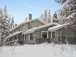Une cabane en rondins avec un toit à forte pente, de nombreuses fenêtres et une cheminée.