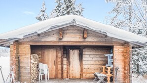 A wooden cabin with a snow-covered roof, a wooden door, and a small porch area with a bench and a table. - Vacation home Mänty by Interhome (Kuusamo)