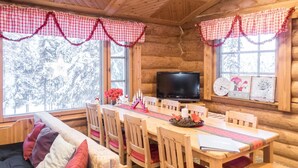 A cozy cabin interior with a wooden dining table, chairs, a sofa, and a television. - Vacation home Mänty by Interhome (Kuusamo)