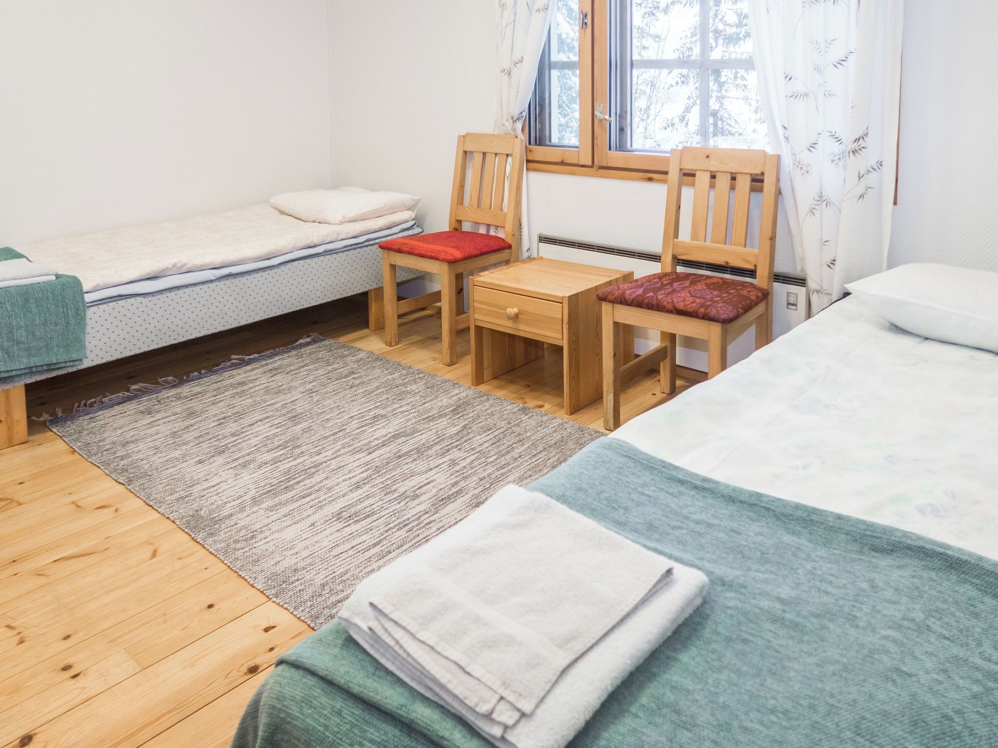 A small, tidy room with a single bed, a desk, and a chair.