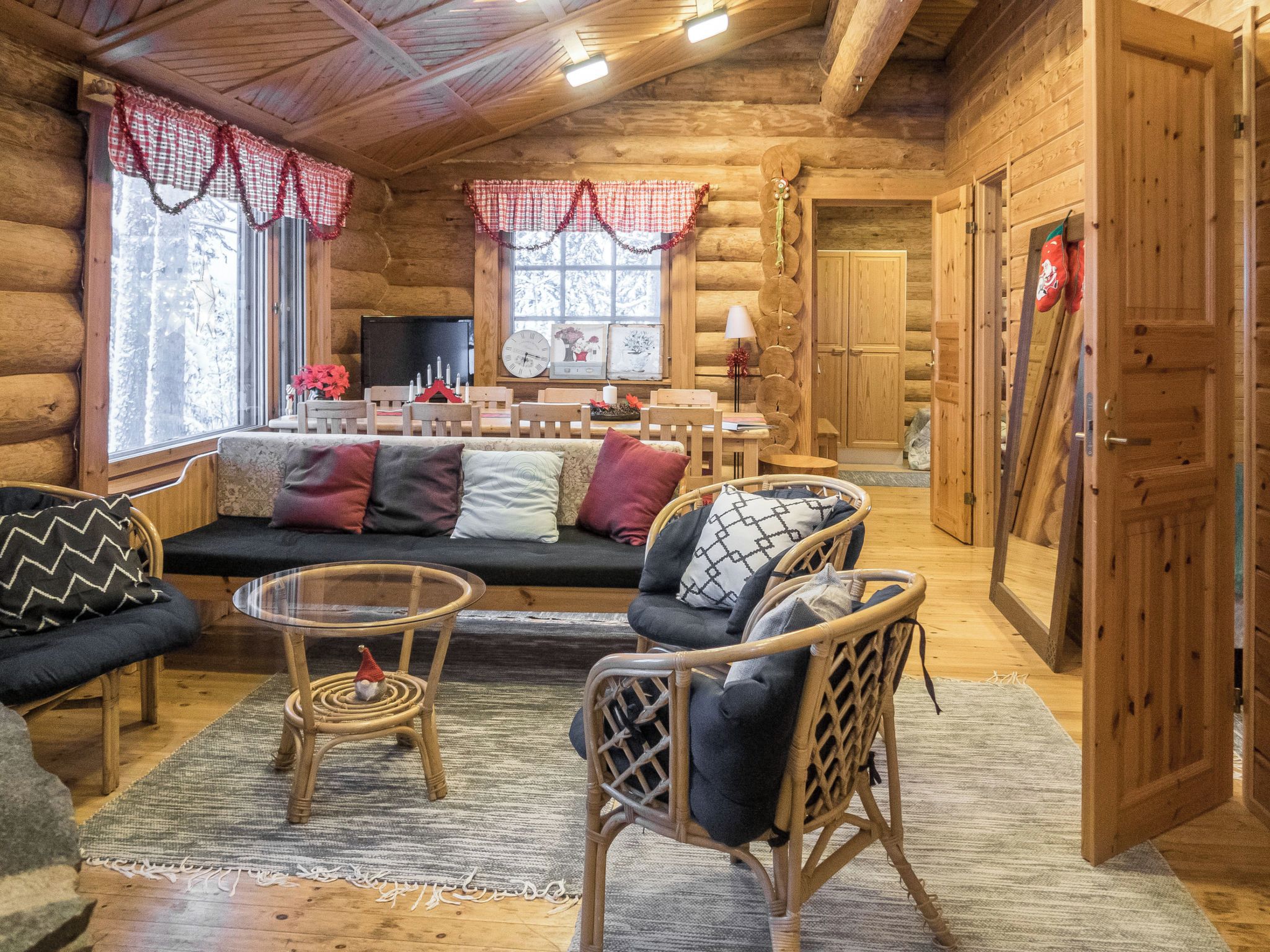 A cozy log cabin interior with a sofa, chairs, a small table, and a television.