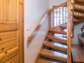 Una escalera de madera con barandilla y un ventanal en la parte superior.