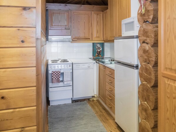 Une cuisine de taille réduite, dotée de meubles en bois, d’une cuisinière blanche, d’un lave-vaisselle et d’un réfrigérateur.