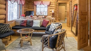 A cozy log cabin interior with a sofa, chairs, a dining table, and a fireplace. - Vacation home Mänty by Interhome (Kuusamo)