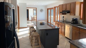 A modern kitchen with wooden cabinets, a central island, and a dining area with chairs. - Beautiful Mountain House with amazing views 11min from Mountain Creek & Warwick (Vernon Township)
