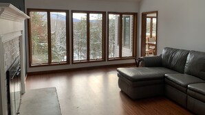 A spacious living room with a large window, a fireplace, and a leather sofa. - Beautiful Mountain House with amazing views 11min from Mountain Creek & Warwick (Vernon Township)