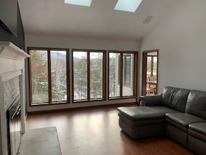 A spacious living room with a large window, a fireplace, and a leather sofa.