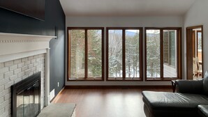 A spacious living room with a fireplace, large windows, and a skylight. - Beautiful Mountain House with amazing views 11min from Mountain Creek & Warwick (Vernon Township)