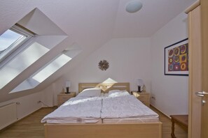A bedroom with a skylight, a bed, bedside tables, and a wall clock. - Courtyard residence - quiet location and with garden use, close to the sea - Höftresidenz (Middelhagen)