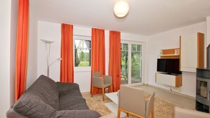 A modern living room with a sofa, chairs, a TV, and a fireplace. - Beachfront vacation rental with a terrace, access to the pool and sauna - Rex Rugia - Rex (Göhren)