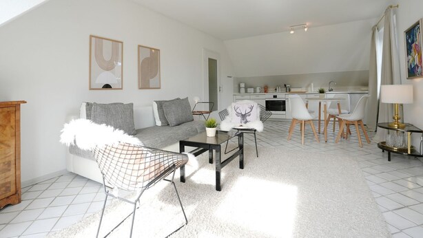 A modern living room with a sofa, chairs, a coffee table, and a dining area with chairs and a table.