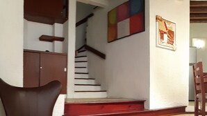 A staircase with red steps leading to a landing, a brown leather chair, and a wooden table.