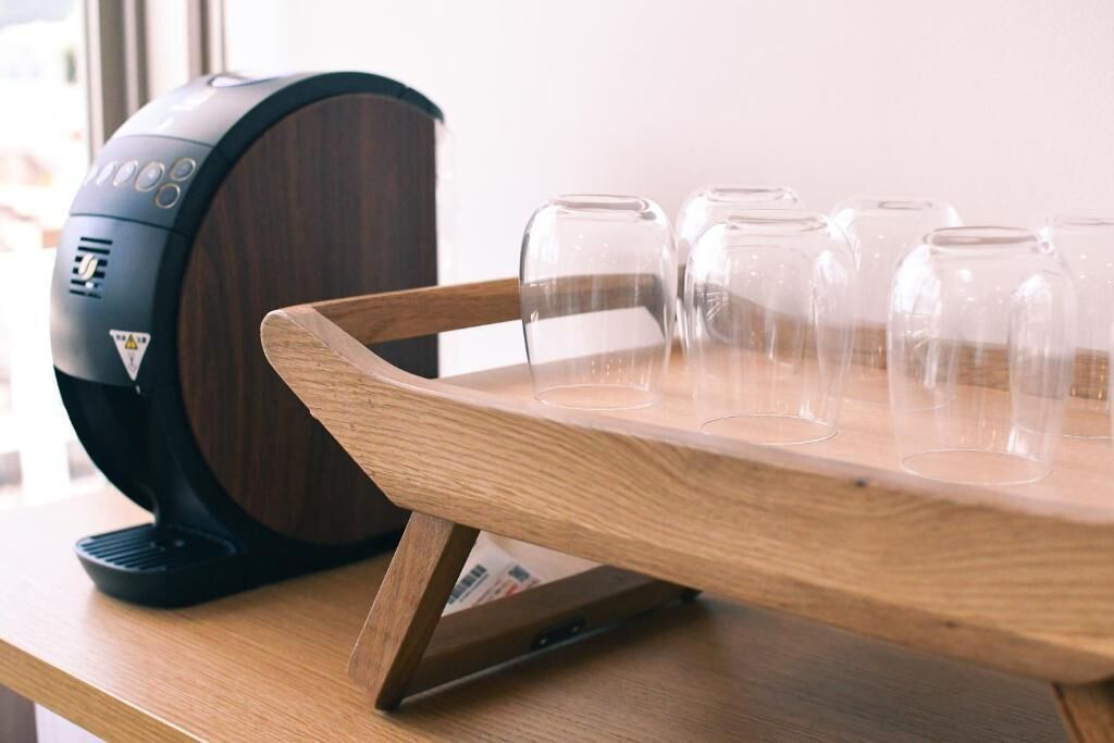 Una cafetera y una bandeja de madera con varios vasos de vidrio sobre una mesa de madera.