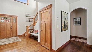 Un pasillo con suelo de madera, una escalera y un banco.