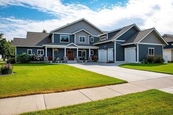 A two-story house with a front porch, a garage, and a well-maintained lawn.