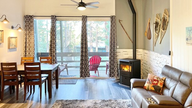 A cozy living room with a fireplace, wooden furniture, and a view through large windows. - Renovated & spacious 2 bed/2 bath Condo with Mountain Views - near Eagle Lodge  (Mammoth Lakes)
