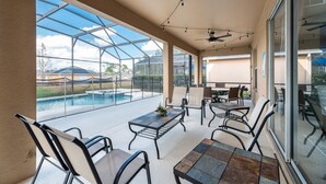 An outdoor patio with a glass enclosure, a pool, and seating arrangements.