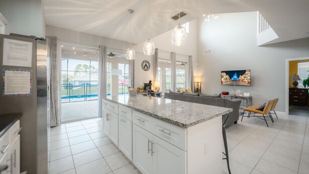 A modern kitchen with a large island, white cabinetry, and pendant lighting.